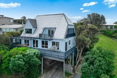 Marengo Views — a classic coastal weatherboard home with elevated deck, pergola, and covered carport, set amongst native coastal gardens in quiet Marengo.