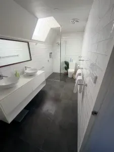 Bright modern bathroom with skylight, double vanity, and walk-in shower