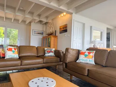 Downstairs living room with new leather sofas, exposed beam ceiling, and coastal touches — the perfect spot to unwind after a day on the Great Ocean Road.
