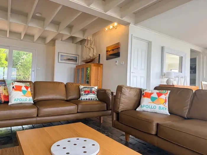 Downstairs living room with new leather sofas, exposed beam ceiling, and coastal touches — the perfect spot to unwind after a day on the Great Ocean Road.