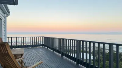 Spacious oceanfront deck with rocking chairs and stunning sunset views