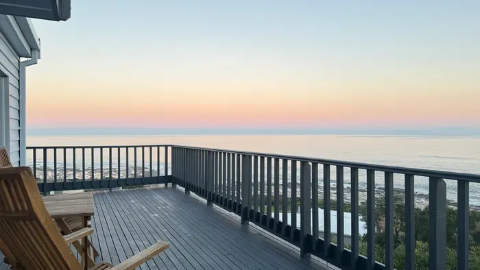 Spacious oceanfront deck with rocking chairs and stunning sunset views