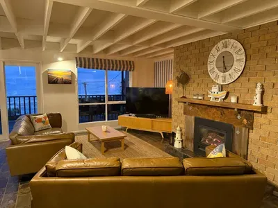 Cozy coastal living room with fireplace, balcony views, and warm rustic charm