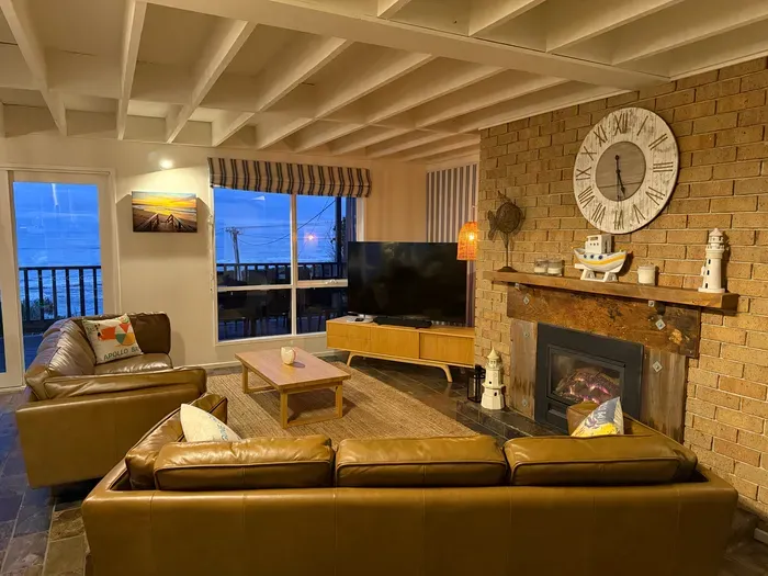Cozy coastal living room with fireplace, balcony views, and warm rustic charm