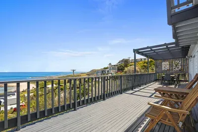 Wrap-around clifftop deck with teak sunloungers and alfresco dining — morning sun, ocean breeze, and views across the Marengo Reef.