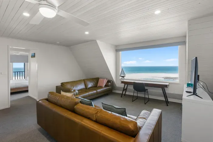 A spacious upstairs retreat with comfortable seating, a dedicated workspace and sweeping Southern Ocean views.