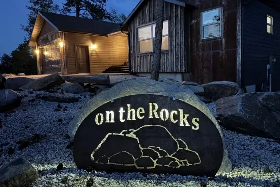 Beautifully lit and thoughtfully landscaped, the front of the home welcomes you with custom rockwork and the signature “On The Rocks” sign—easy to spot, even after dark.