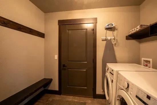 This laundry room features a full-size washer and dryer, bench for putting on shoes, and direct access to the garage—perfect for gearing up or cleaning up.