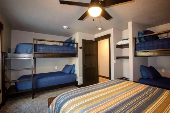 This lower-level room sleeps up to six with a queen bed and 2 sets of twin bunks—perfect for families, cousins, or a fun sleepover-style setup for the kids.