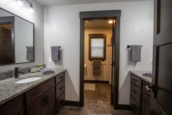 This lower-level bathroom features dual vanities and a separate toilet/shower area—perfect for groups or families getting ready at the same time.