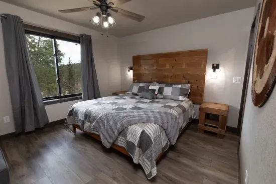 Upper-level king ensuite with a comfortable king bed and peaceful Black Hills forest views. This private bedroom includes its own attached bathroom, creating a quiet retreat upstairs.
