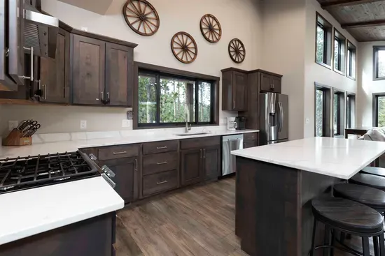 Bright kitchen at Quittin’ Time with a large island, stainless appliances, and windows overlooking the pines. Plenty of counter space for cooking together before heading out to explore the Black Hills.