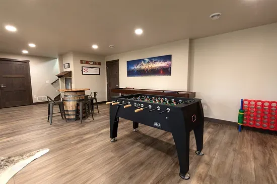 Lower-level game room featuring foosball, shuffleboard, Connect Four, and a barrel pub table—perfect for friendly competition and relaxing after a day in the Black Hills.