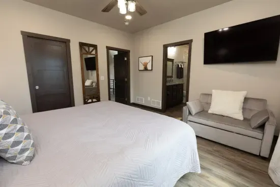 Main-level king ensuite at Quittin’ Time with forest views, a private bathroom, and a spacious closet. A comfortable retreat for guests who prefer a private bedroom on the main floor.