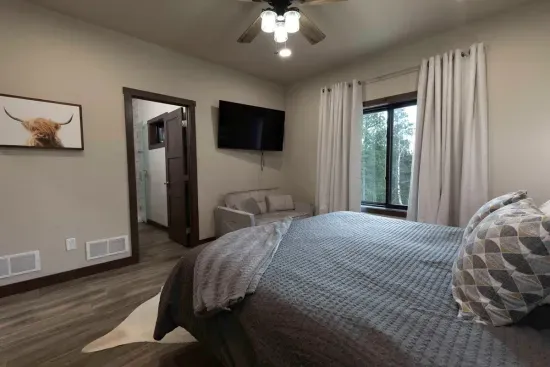 Main-level king ensuite at Quittin’ Time with forest views, a private bathroom, and a spacious closet. A comfortable retreat for guests who prefer a private bedroom on the main floor.