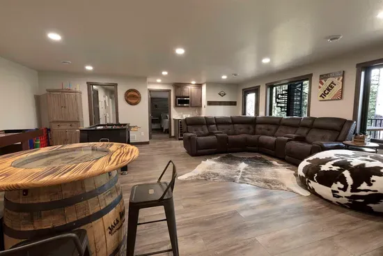 Spacious lower-level entertainment area with large sectional seating, foosball, shuffleboard, pub table, and a wet bar—perfect for movie nights, game time, and relaxing together after a day in the Black Hills.