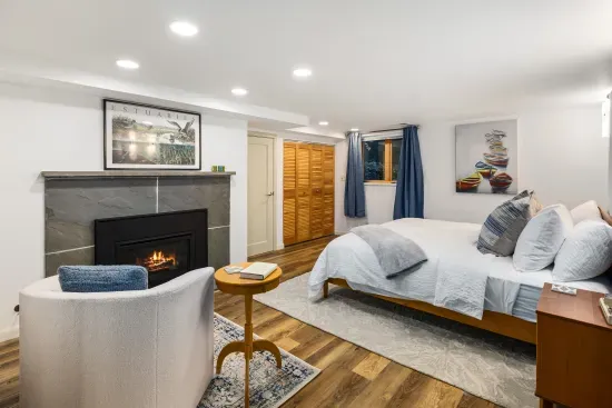 King bed with a gas fireplace and wood framed windows with a garden view.
