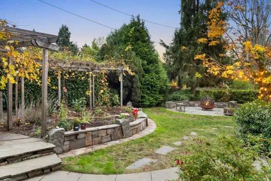 Guests are invited to walk through the grape arbor and enjoy the circular stone patio with firepit