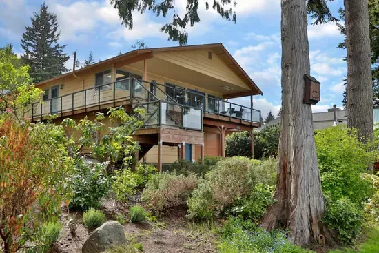 The house sits up from the road and has a glass fenced in deck the surrounds 3/4 of the house.   Note the ceiling heater above the outside dining table.