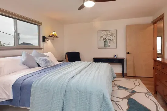 The spacious primary suite boasts a king bed atop a cozy area rug. Soothing colors make for a restful night’s sleep. Other amenities include dual nightstands and lamps, a dresser, and a corner leather chair for a few minutes of alone time.  Doors to