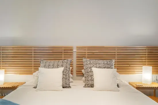 The spacious ground-floor bedroom features a low-profile king bed with a 3" high-quality mattress topper, side tables with reading lamps, a cozy reading chair, and ample space for guests using a walker or wheelchair.