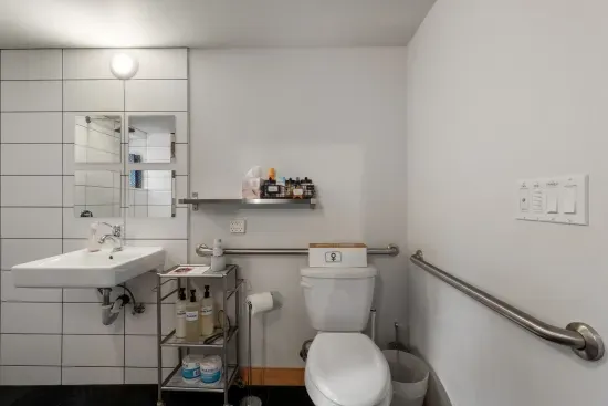 This ADA compliant ground bathroom has grab bars and handrails, a wheel-under sink, and soaps, shampoo, and conditioner.