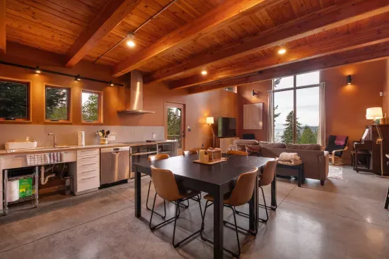 The open-concept kitchen and dining area, featuring wood beam ceilings, and seats six at the table and two at the nearby counter.