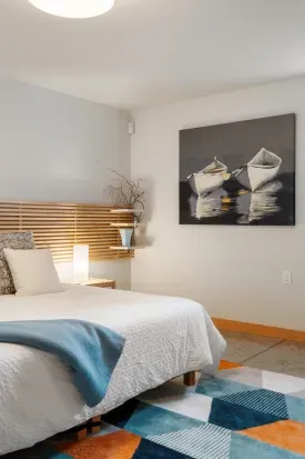 The spacious ground-floor bedroom features a low-profile king bed with a 3" high-quality mattress topper, side tables with reading lamps, a cozy reading chair, and ample space for guests using a walker or wheelchair.