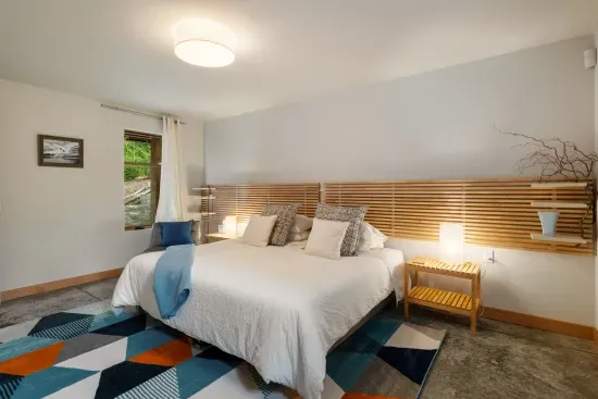 The ground floor, spacious bedroom includes a low profile king bed,  with 3" high quality mattress topper, side tables with reading lamps, a reading chair, and plenty of room for folks who use a walker or wheelchair.