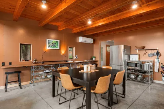 The open-concept kitchen and dining area, featuring wood beam ceilings, and seats six at the table and two at the nearby counter.