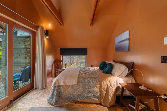 The second floor King bedroom with a block out shade, two side tables and lamps, also includes a set of glass doors that lead to a private deck.