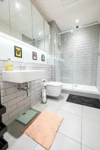 Walk-in glass rainfall shower, metro tiles and backlit mirrored cabinets — finished with fresh towels, hotel-standard clean.
