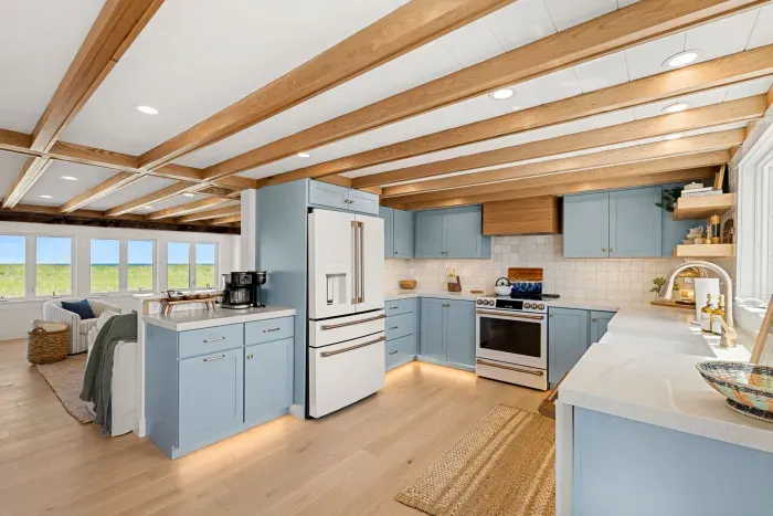 Bright coastal kitchen with blue cabinetry, open layout, and sunny views