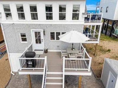 Spacious beach-house deck with dining area, grill, and sunny outdoor seating