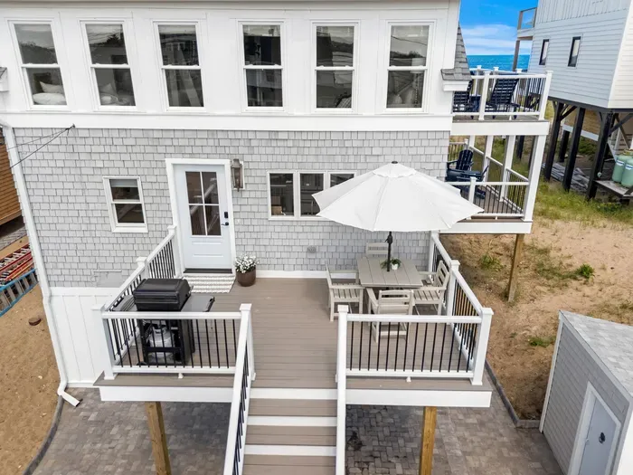 Spacious beach-house deck with dining area, grill, and sunny outdoor seating
