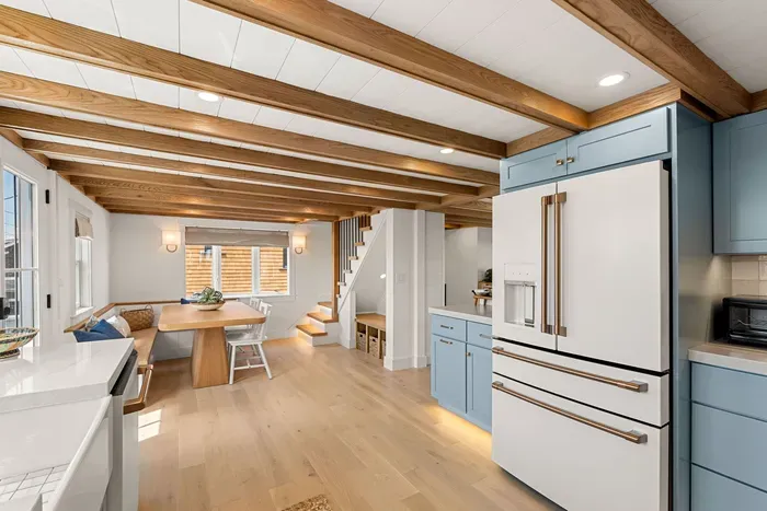 Bright farmhouse kitchen with wood beams, blue cabinets, and cozy dining nook