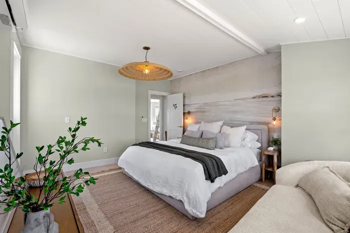 Calming coastal-style bedroom with plush bed and warm designer touches