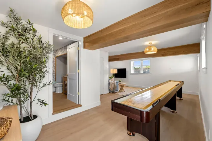 Bright game room with shuffleboard, TV, and beautiful wood beam accents