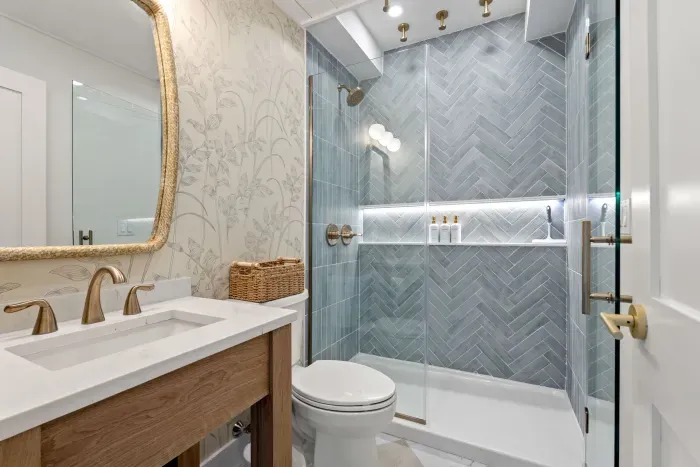 Spa-like bathroom with glass shower, brass accents, and designer tile