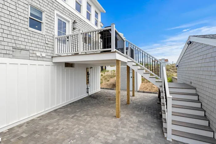 Raised deck with grill, stairs, and spacious paved patio below
