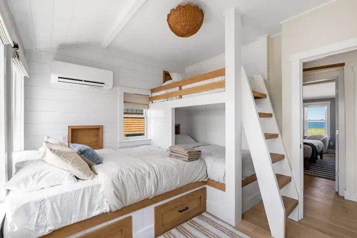 Bright custom bunk room with loft bed, storage, and airy coastal style