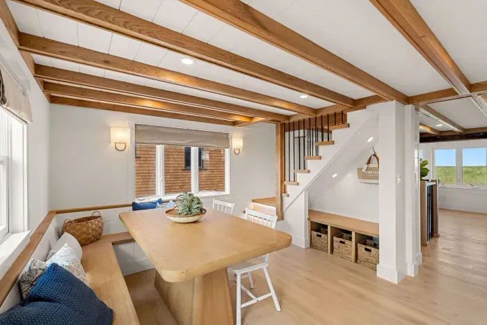 Bright dining nook with built-in seating, wood beams & stylish storage