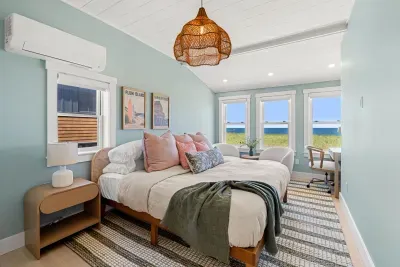 Bright coastal bedroom with ocean views, seating nook, and workspace