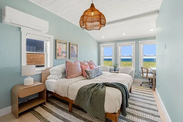 Bright coastal bedroom with ocean views, seating nook, and workspace