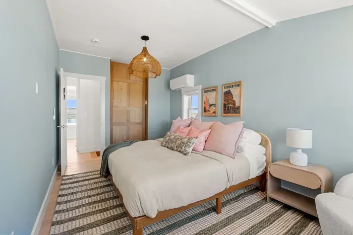 Bright coastal bedroom with plush bedding, stylish decor, and AC