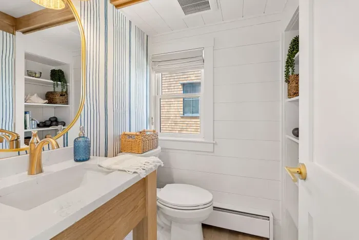 Bright coastal bathroom with gold accents and stylish built-in storage