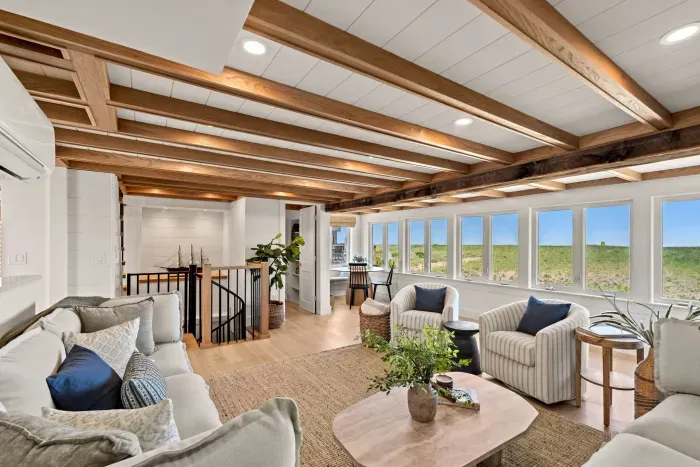 Sun-filled living room with exposed beams and serene coastal views