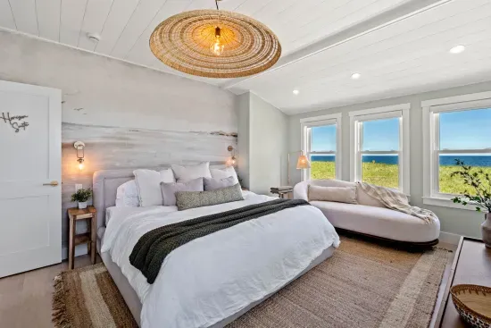 Bright coastal bedroom with ocean views, king bed, and cozy chaise lounge