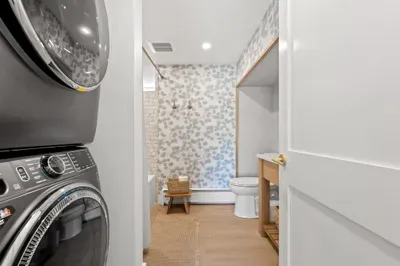 Stylish bath with in-unit washer/dryer and charming floral wallpaper