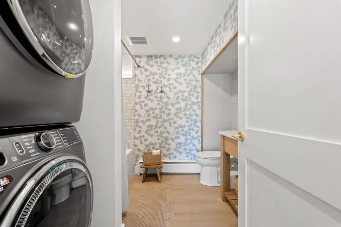 Stylish bath with in-unit washer/dryer and charming floral wallpaper